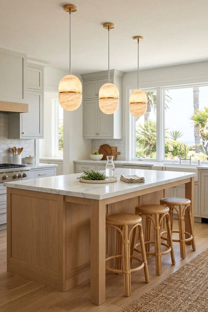 Isaline Banded Capsule Alabaster Pendant Light illuminating a modern kitchen with natural light.