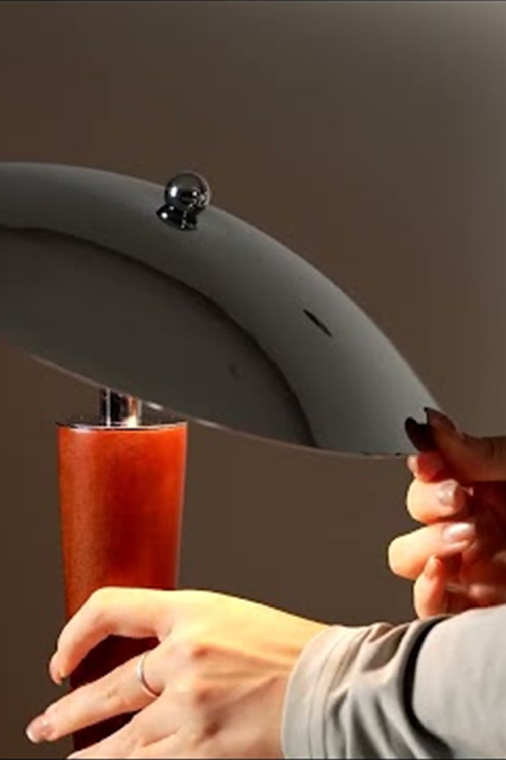 Isolde Domed Walnut Table Lamp | Adjusting Shade Detail | Detailed close-up shot showing a person's hand adjusting the sleek polished chrome dome shade of the lit table fixture | Detail shot | vexa lamps
