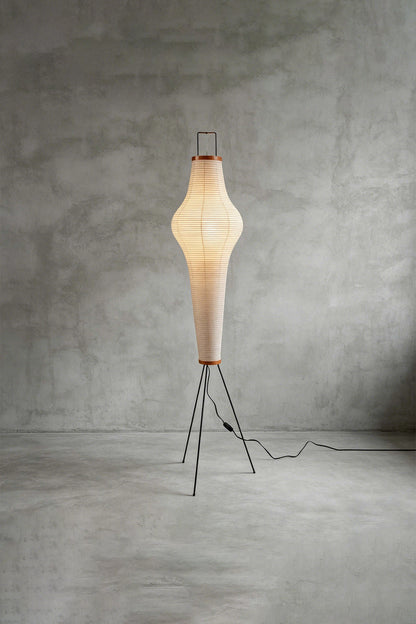 Isolde Ribbed Paper Column Floor Lamp standing on a slim metal frame, glowing softly from within, perfect for cozy spaces.