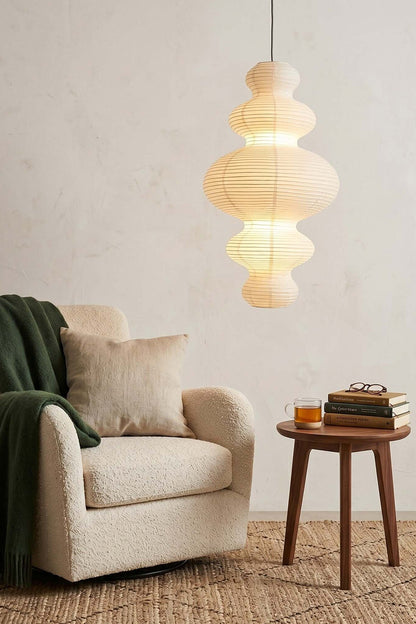 Isolde Stacked Paper Pendant Lamp | Textured Ribbed Paper | Casting soft light over a cozy reading corner with a plush cream armchair and side table | vexa lamps