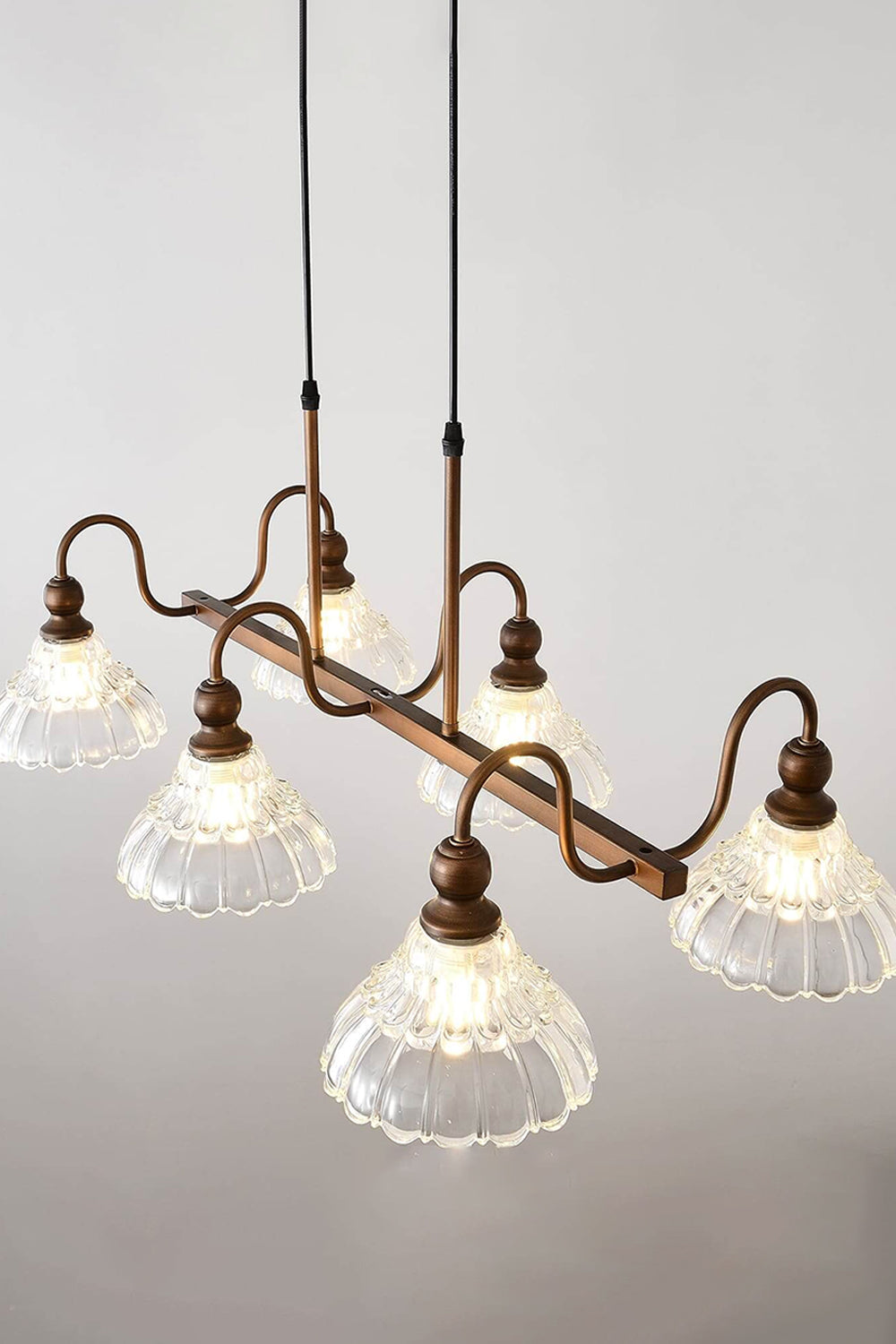 Isolde Vintage Glass Long Chandelier | High Angle Studio View | Studio perspective shot looking slightly down at the illuminated linear bronze and glass island fixture showcasing its elongated shape | vexa lamps