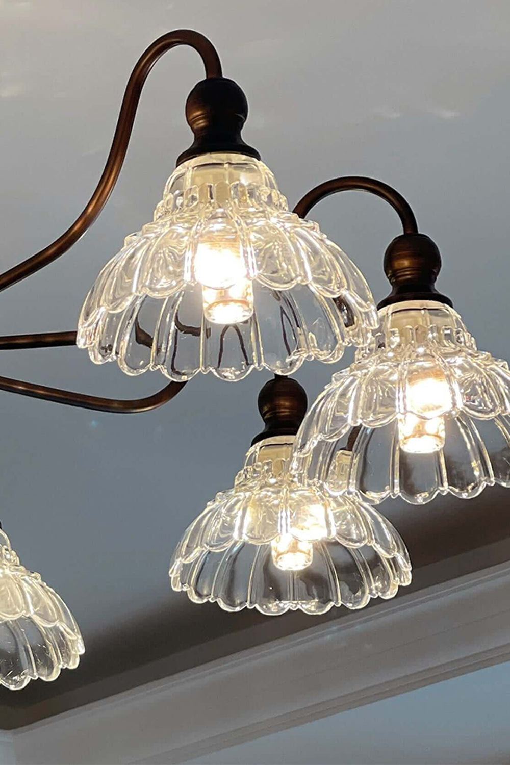 Isolde Vintage Scalloped Glass Chandelier | Looking Up View | Studio perspective view looking up at the illuminated ruffled clear glass shades radiating a bright warm glow | vexa lamps