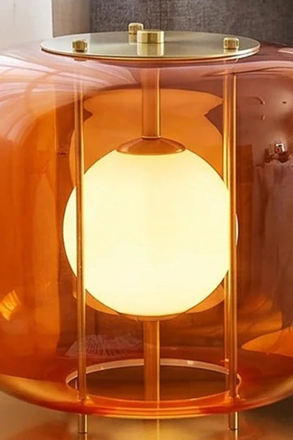 Jasper Colorblock Table Lamp | Glass, Metal | Macro close-up focus on the illuminated orange glass variant showing the top brass plate, structural wires, and frosted white light bulb globe | Detail shot | vexa lamps