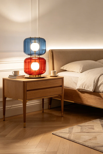Jasper Colorblock Table Lamp | Glass, Metal | Closer room view of the colorful stacked glass lamp radiating warm light on a bedroom nightstand with linen textures | vexa lamps