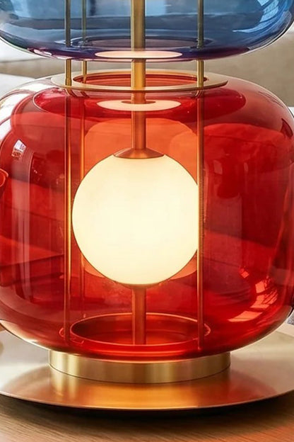 Jasper Colorblock Table Lamp | Glass, Metal | Detailed close-up view focusing on the glowing red translucent glass lower block and the circular brushed gold brass base plate | Detail shot | vexa lamps