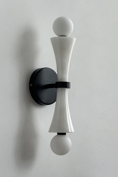 Katia Travertine Hourglass Wall Lamp | Travertine, Metal | Studio variant product view featuring a smooth white marble or stone hourglass body paired with black hardware fittings | vexa lamps