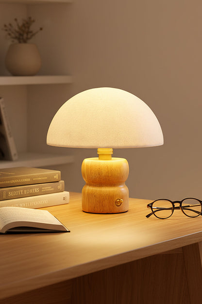 Kira Sculpted Mushroom Table Lamp | Wood, Glass | Close-up shot of the fully illuminated lamp casting a cozy golden glow on a desk with open books and glasses | vexa lamps