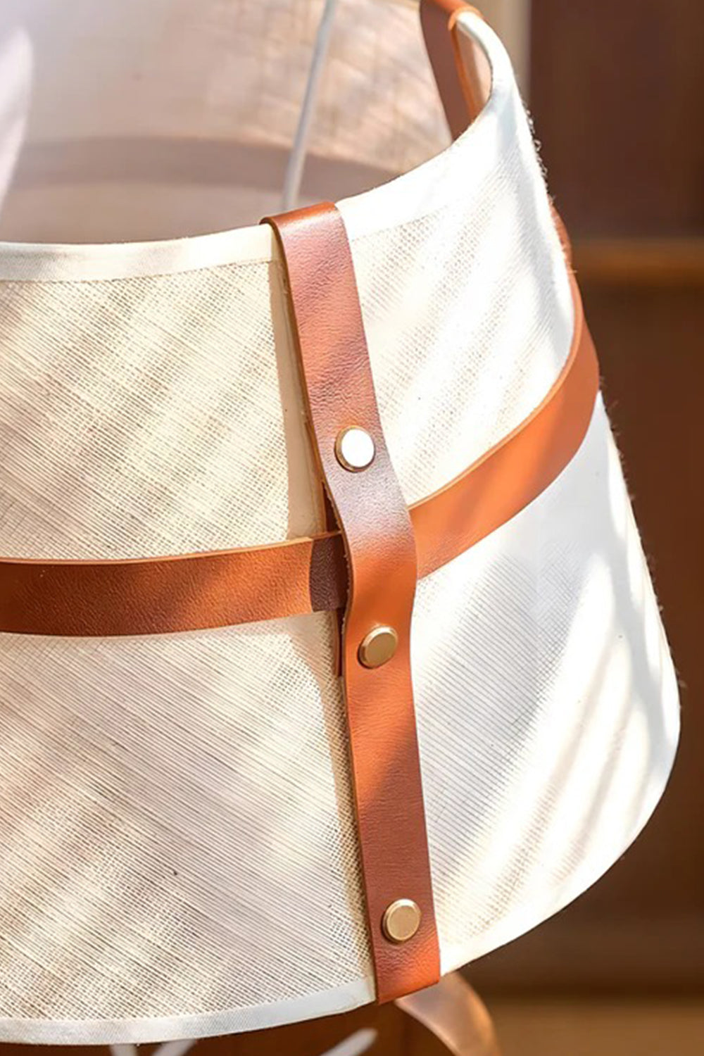 Leafora Botanical Leaf Table Light | Wood, Fabric, Leather | Close-up focus on the cream woven fabric lampshade highlighting the detailed brown leather intersecting straps and metal rivet button | Detail shot | vexa lamps