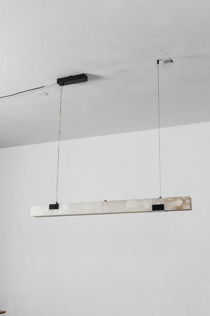 Liora Linear Alabaster Pendant Light | Natural Alabaster and Black Metal | Full studio product view of the unlit long linear fixture hanging from slim ceiling wires | vexa lamps
