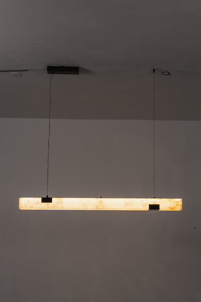 Liora Linear Alabaster Pendant Light | Natural Alabaster and Black Metal | Minimalist full view of the illuminated linear pendant light glowing in a dimly lit environment | vexa lamps