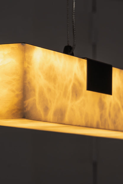 Liora Linear Alabaster Pendant Light | Natural Alabaster and Black Metal | Detailed macro shot focusing on the warm light filtering through the marbled stone texture | vexa lamps