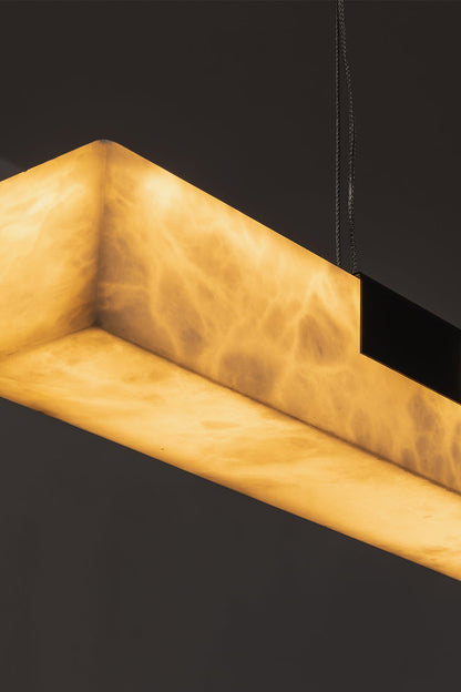 Liora Linear Alabaster Pendant Light | Natural Alabaster and Black Metal | Close-up macro view highlighting the corner of the glowing alabaster stone and a black bracket | vexa lamps
