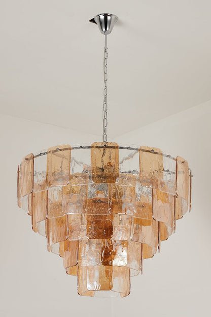 Lucia Tiered Amber Glass Chandelier | Glass, Metal | Studio front view of the fully illuminated multi-tier amber glass chandelier casting a warm golden light against a grey backdrop | vexa lamps