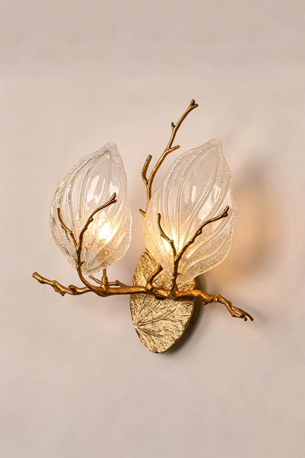 Magnolia Arbor Brass Wall Lamp | Brass, Glass | Frontal angled view of the fully lit organic brass lamp against a warm plain backdrop | Isolated shot | vexa lamps