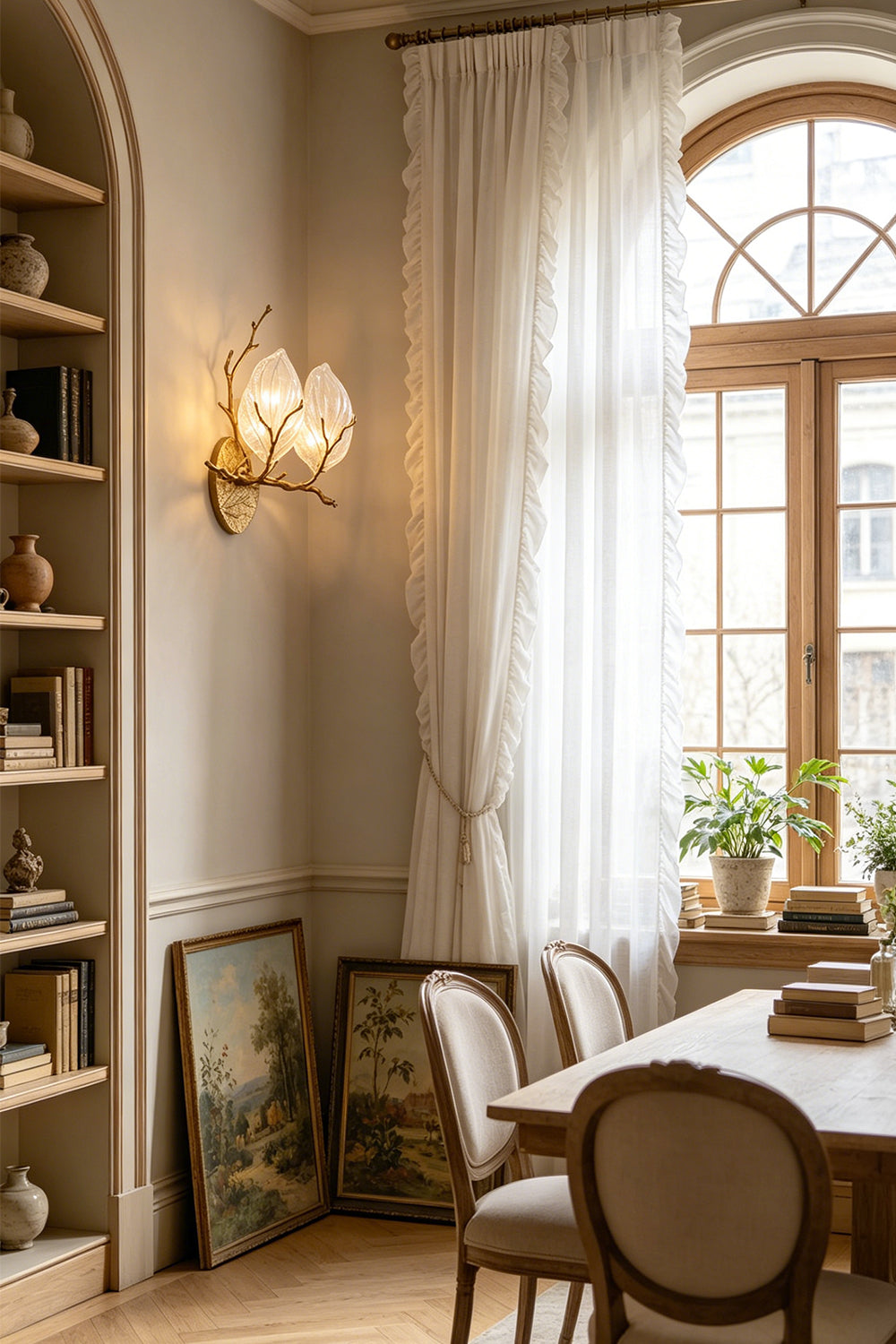 Magnolia Arbor Brass Wall Lamp | Brass, Glass | Mounted on a wall near a classic wooden dining table and bookshelves in a room with a large arched window | vexa lamps