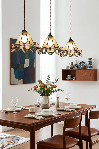 Mariposa Canopy Stained Glass Pendant Lamp | Glass, Metal | A row of three matching stained glass pendants suspended over a long dark wood dining table and chairs | vexa lamps