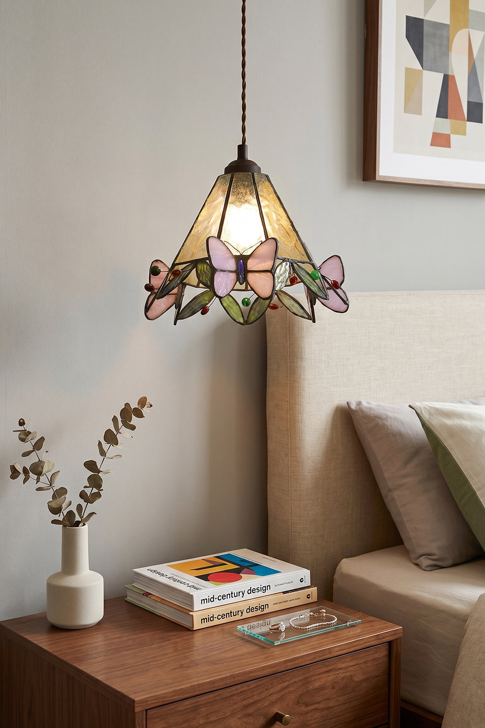 Mariposa Canopy Stained Glass Pendant Lamp | Glass, Metal | Positioned as a warm bedside pendant light over a wooden nightstand with books next to a upholstered bed | vexa lamps