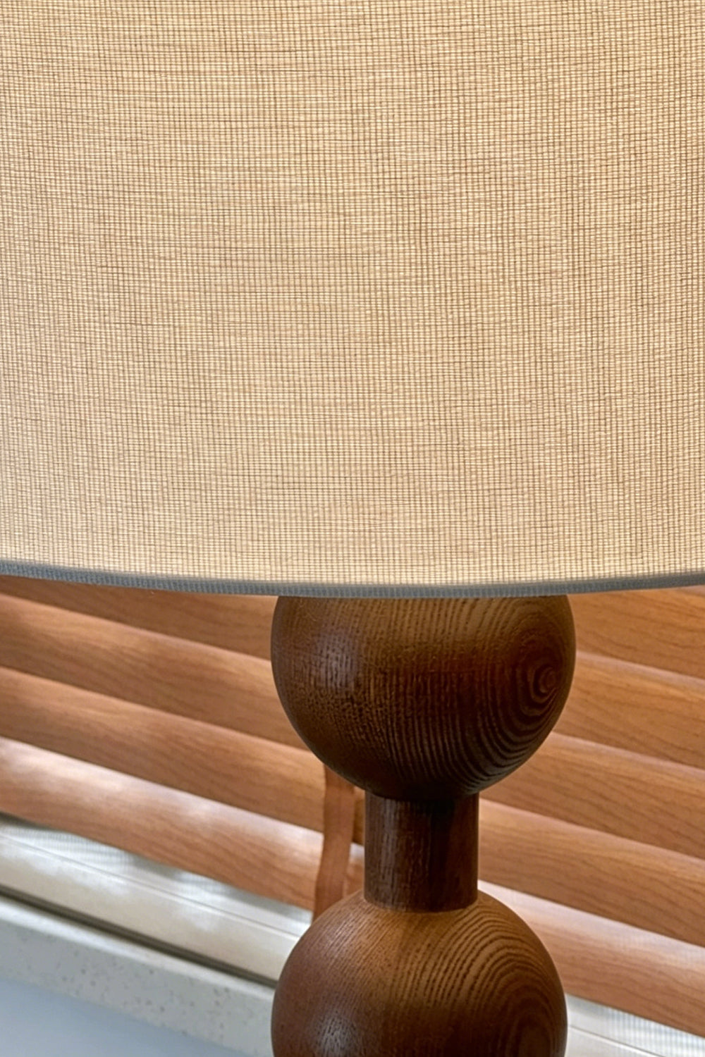 Marlow Stacked Wood Floor Lamp | Wood, Fabric | Detailed close-up view highlighting the textured beige linen drum lampshade meeting the top dark walnut wooden sphere | Detail shot | vexa lamps