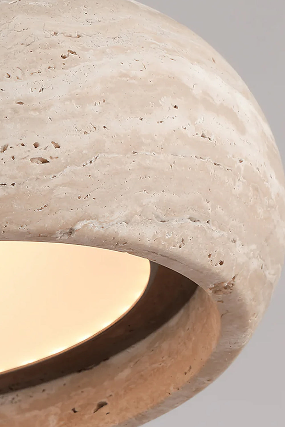 Maro Travertine Donut Pendant Light | Travertine, Metal | Close-up side profile view of the lit travertine donut shade highlighting its porous pitted texture and soft warm downlight | Detail shot | vexa lamps