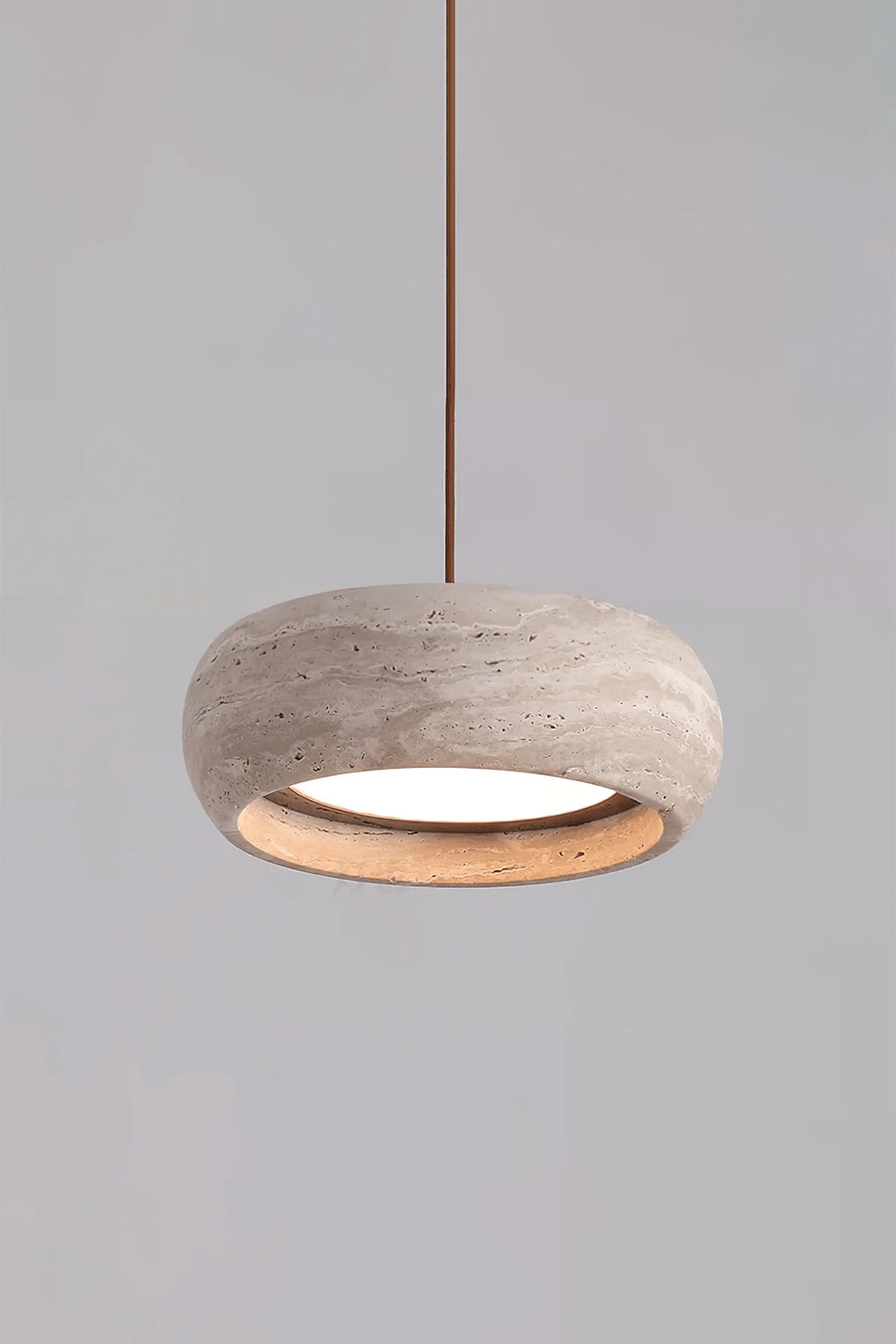 Maro Travertine Donut Pendant Light | Travertine, Metal | Studio product view of the fully illuminated travertine donut pendant light casting a cozy golden halo on a grey background | vexa lamps