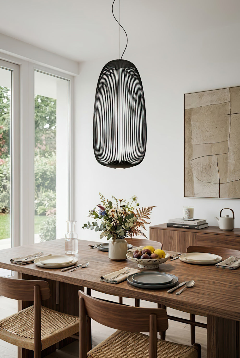 Black elliptical wire cage lamp in dining room | Aluminum | Over a wooden table with chairs and plants | vexa lamps