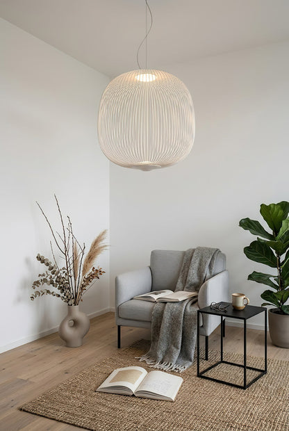 White wire cage pendant light over a reading chair | Aluminum | Cozy corner scene with a grey armchair | vexa lamps