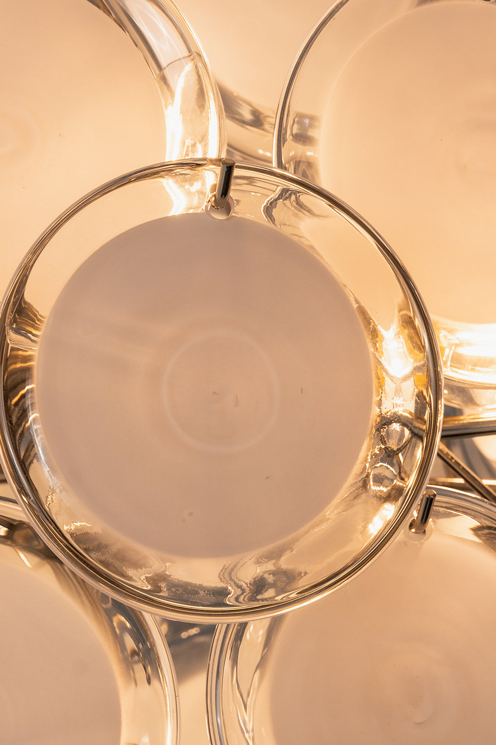 Mirella Circular Glass Pane Ceiling Light | Illuminated Detail | Close-up macro view of a single glowing white circular glass disc panel radiating soft warm light from the internal bulb | Detail shot | vexa lamps