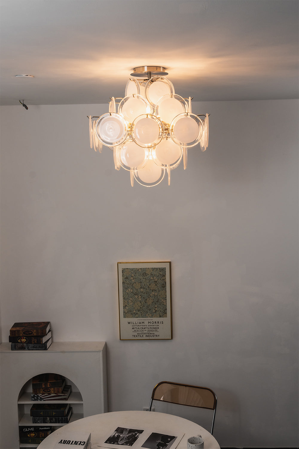 Mirella Circular Glass Pane Ceiling Light | Room Staged View | Studio lit display of the modern multi-glass disc ceiling light hanging against a plain wall above a minimalist table | vexa lamps