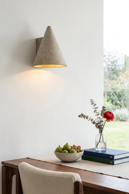 Monolith Cone Travertine Wall Sconce illuminating a dining area with fruit bowl and flowers on the table.