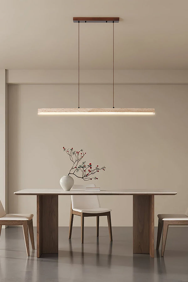 Modern organic linear pendant lamp | Travertine, Wood, Acrylic | Centered in a bright minimalist room over a simple table | vexa lamps