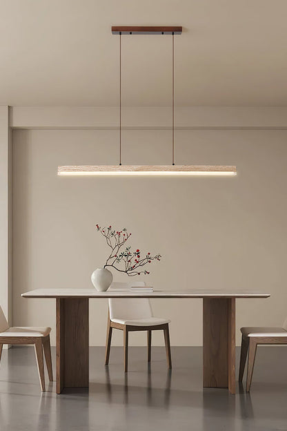 Modern organic linear pendant lamp | Travertine, Wood, Acrylic | Centered in a bright minimalist room over a simple table | vexa lamps
