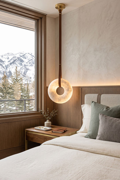 Nerissa Alabaster Ring Leather Pendant Light | Natural Alabaster, Leather and Brass | Suspended beside a bed over a nightstand in a mountain view bedroom | vexa lamps