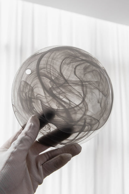 Nimbus Smoked Glass Disc Chandelier handmade glass disc showcasing swirling smoke design in hand.