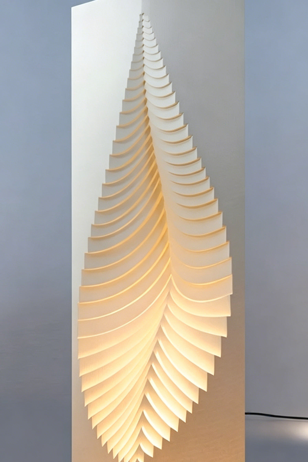 Nori Sculptural Leaf Floor Lamp | Fabric, Wood | Studio mockup shot of the tall column lamp glowing softly against a clean light grey backdrop | vexa lamps