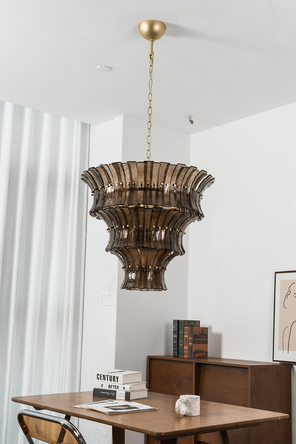Octavia Sculptural Smoked Glass Chandelier | Dining Room Chandelier | Studio staged view of the fully illuminated tall multi-tiered glass fixture casting a warm golden glow near a table | vexa lamps