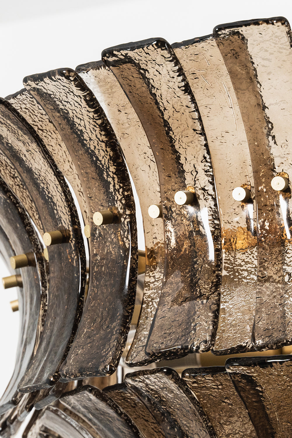 Octavia Sculptural Smoked Glass Chandelier | Overlapping Glass Detail | Close-up structural view focusing on the layered rows of curved smoked glass panels secured by gold metallic pins | Detail shot | vexa lamps