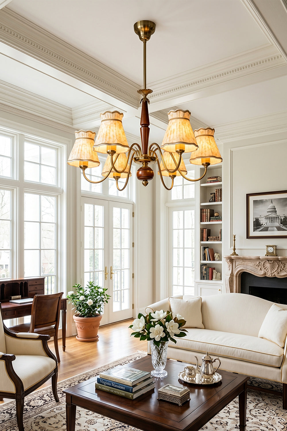 Odette Vintage Pleated Shaded Chandelier | Wood, Brass, Fabric | Hanging as an elegant classical centerpiece in a bright European-style living room featuring white grid windows, a cream sofa, and a fireplace | vexa lamps