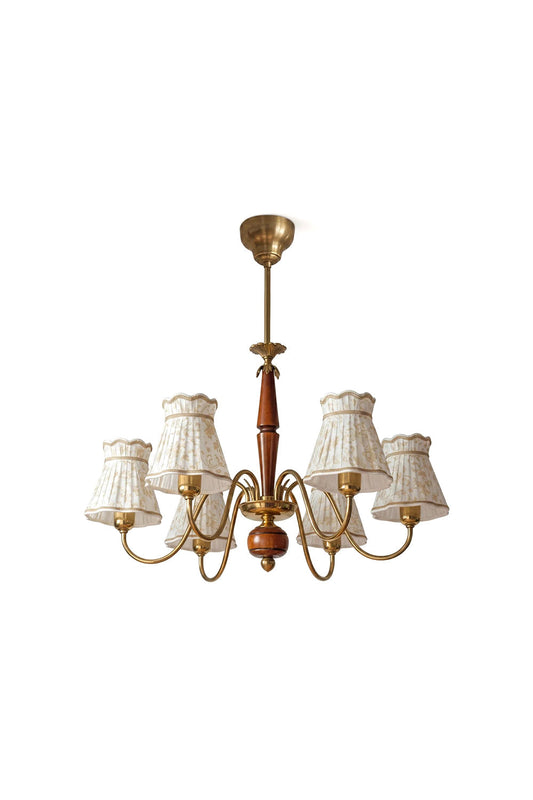 Odette Vintage Pleated Shaded Chandelier | Wood, Brass, Fabric | Isolated unlit view of a traditional 6-arm vintage chandelier featuring cream pleated fabric shades, curved brass scroll arms, and a turned wood central spindle column | White background | vexa lamps
