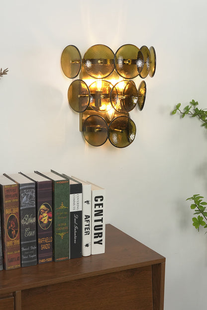 Close-up of lit olive green glass disc lamp | Metal, Glass | Positioned above stacked vintage books | vexa lamps