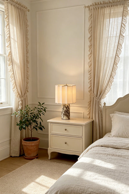 Orbis Veil Pleated Marble Table Lamp on nightstand in a cozy bedroom with soft curtains and a plant.