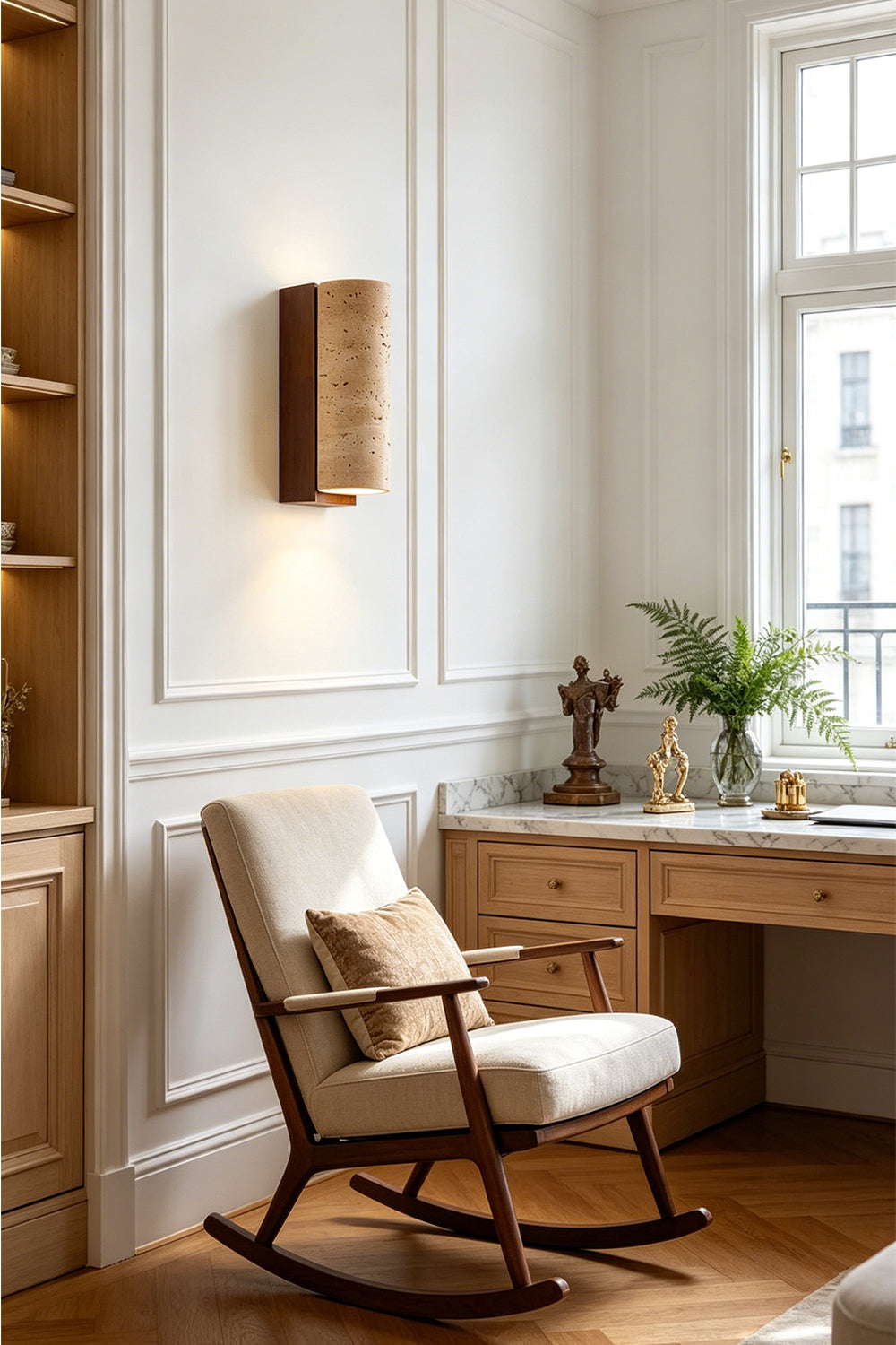 Outcrop Beige Travertine Wall Sconce | Travertine, Metal | Staged gracefully on a living room wall, casting a soft warm light above a white rocking chair with a wooden desk nearby | vexa lamps
