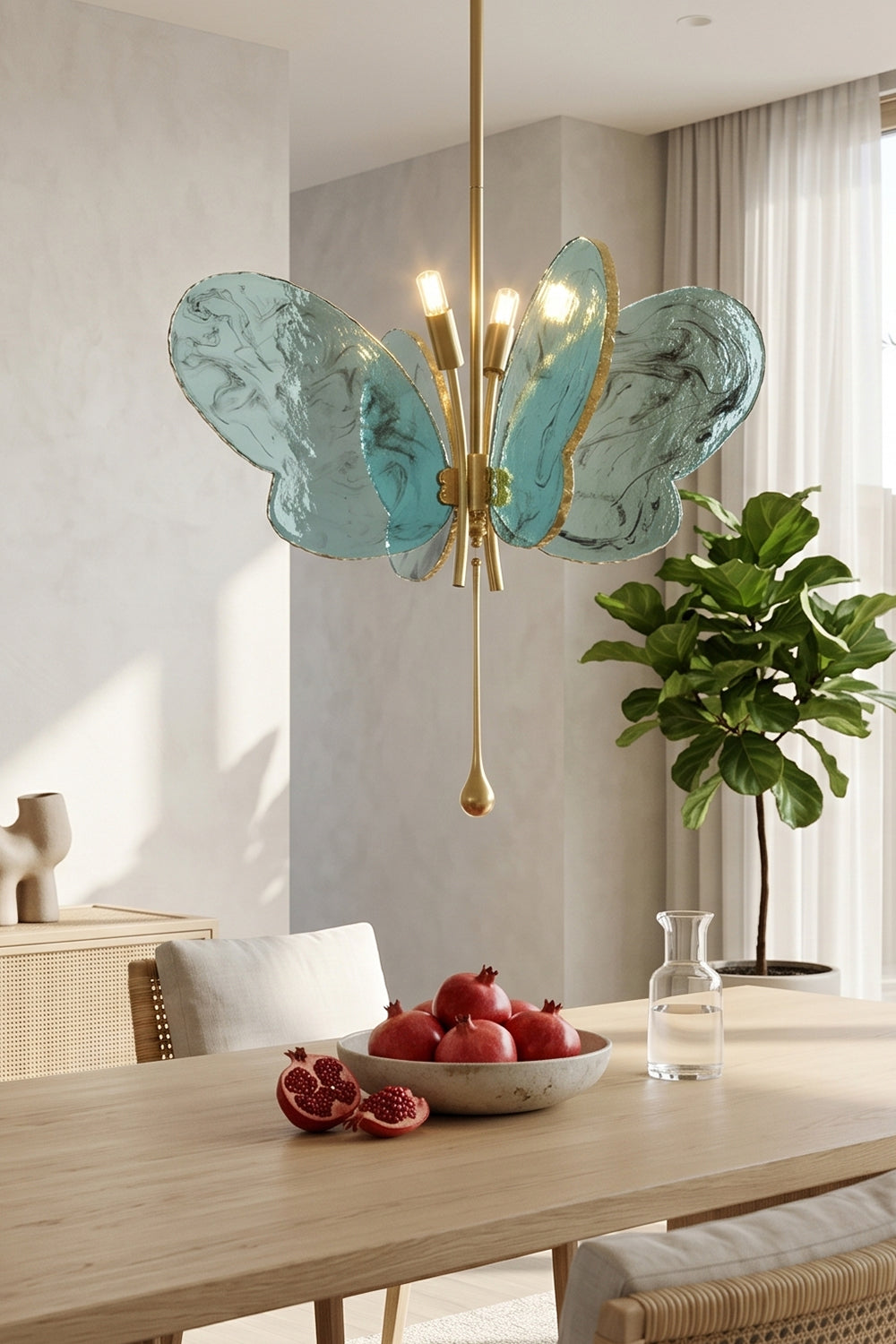 Papillon Glass Butterfly Pendant Lamp | Glass, Metal | Closer view of the glowing blue butterfly fixture over a wooden dining setup decorated with a bowl of red apples | vexa lamps