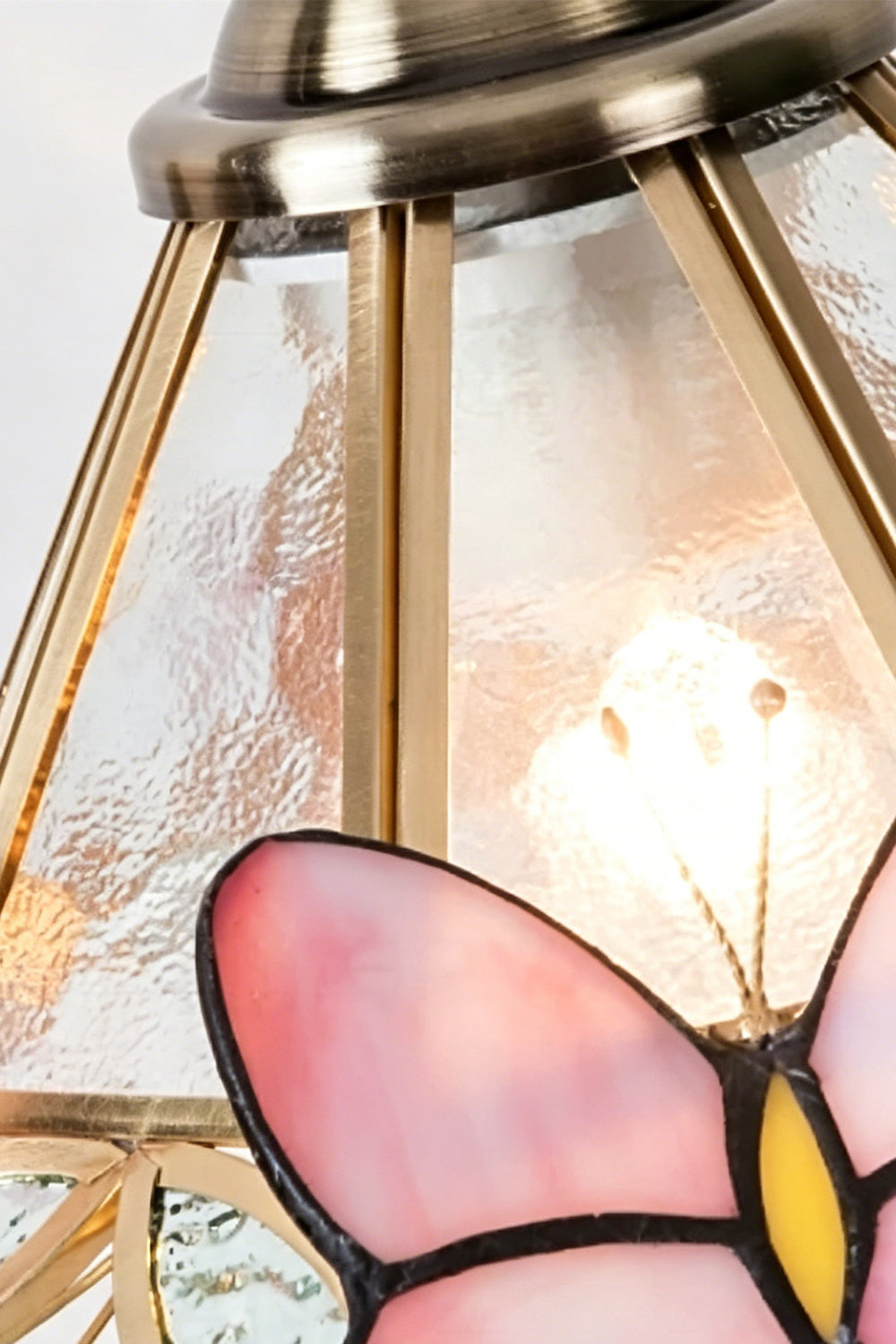 Papillon Heirloom Stained Table Lamp | Wood, Glass, Metal | Macro close-up of the lit textured glass panel, brass framework, and a pink butterfly wing | Detail shot | vexa lamps