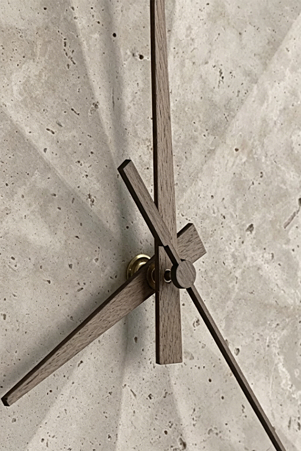Petra Compass Travertine Backlit Wall Lamp | Travertine, Iron | Extreme macro close-up of the dark iron compass-like hands fixed onto the textured travertine surface | Detail shot | vexa lamps