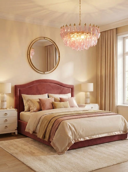 Lit pink glass chandelier in a master bedroom | Metal, Glass | Positioned above a red velvet headboard | vexa lamps