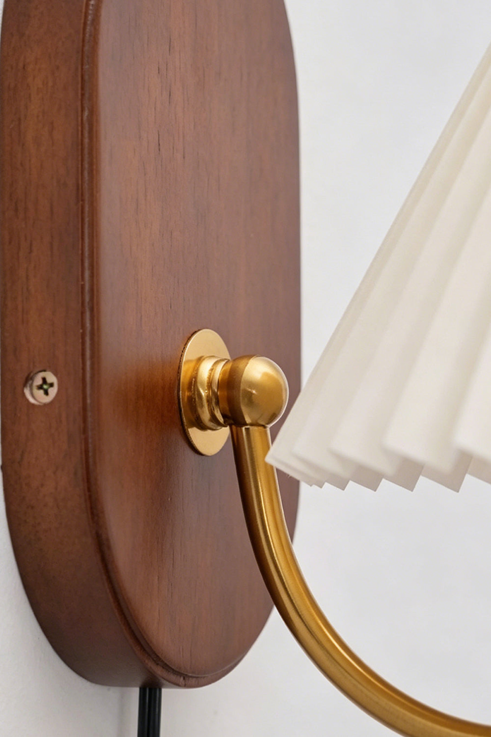 Pleated Fabric Wall Lamp | Fabric, Metal, Wood | Close-up focus on the gold brass swivel joint connected to the smooth polished oval wooden backplate | Detail shot | vexa lamps