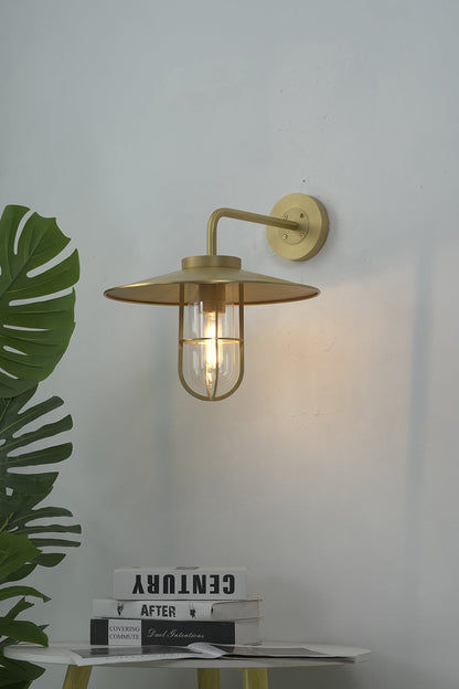 Lit brass nautical wall light on white interior wall | Brass, Glass | Indoor scene with a green plant | vexa lamps