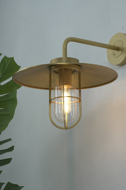 Close-up of lit brass Portree wall sconce | Brass, Glass | Showing the glass cylinder and protective cage | vexa lamps