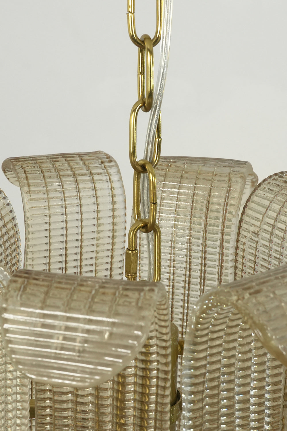 Top section of the ribbed glass scroll chandelier | Metal | Glass | Close-up of the gold chain and glass panel attachment | vexa lamps