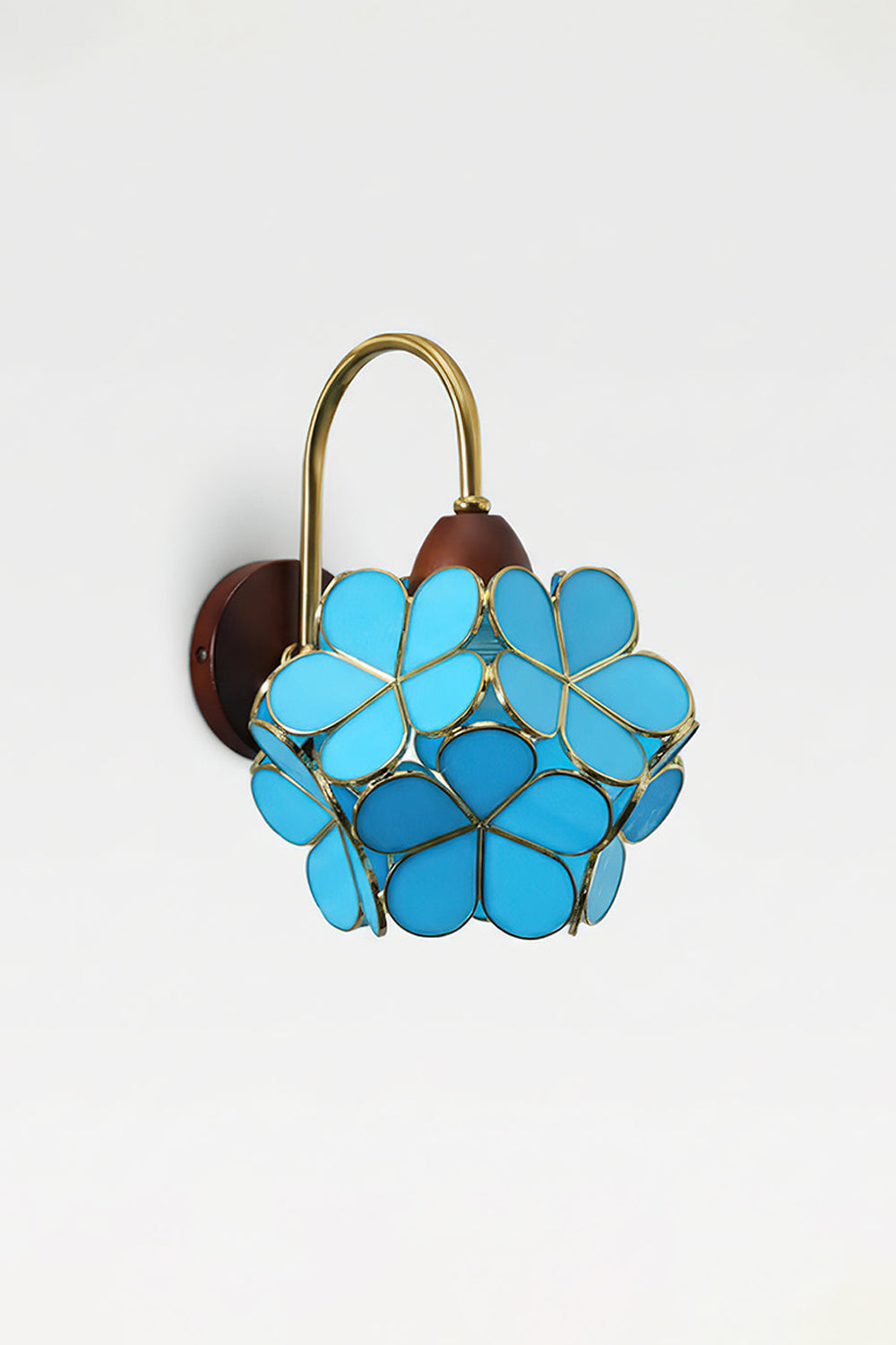 Rosalind Petal Glass Botanical Wall Lamp | Glass, Metal, Wood | Isolated lit product view of the vibrant blue glass petal variant glowing intensely against a white background | vexa lamps